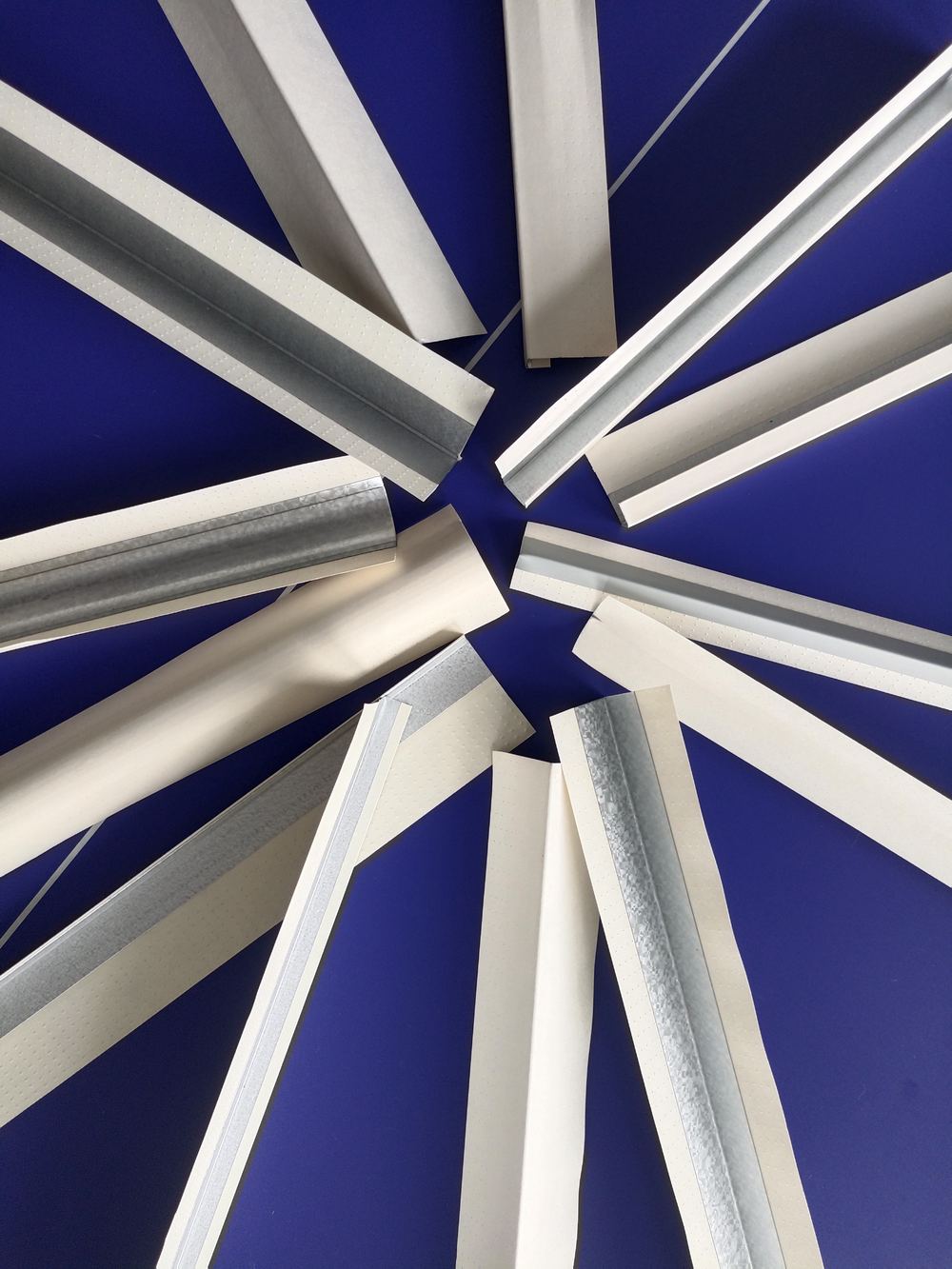 Paper-faced metal corner bead and trim profiles on a blue background